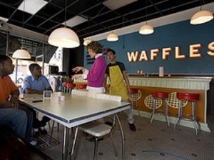 Patrons sit at a classic looking table as a waitress takes their order.