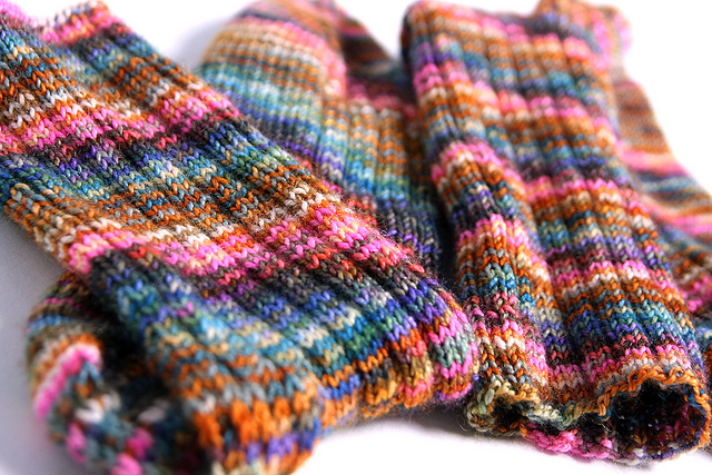 Colorful hand-made knit socks on a white background.