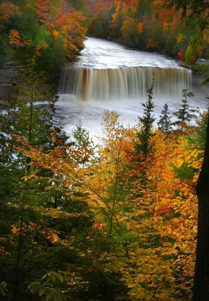 Fall foliage highlights water cascading over Upper Tahquamenon Falls.