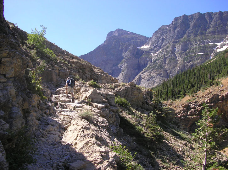 Hiker ascends a rocky trail in Waterton Lakes National Park, Alberta, Canada.
