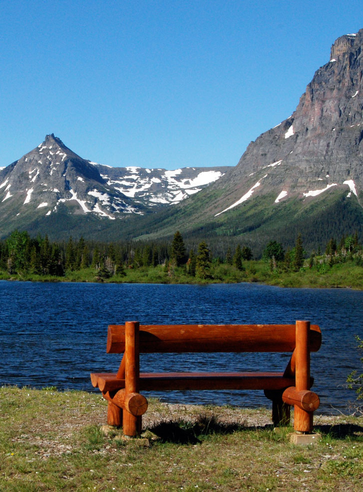 A bench made of logs on the shore of Pray Lake in Glacier National Park.