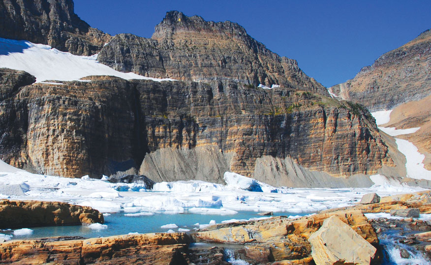 Ice and snow cluster around exposed striated rock.