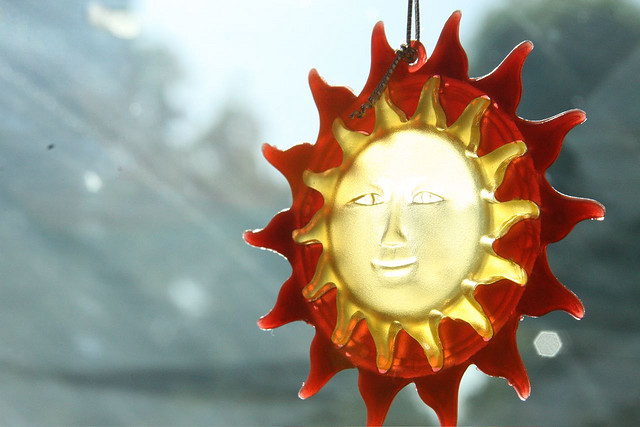 Light filters through a window into a glass bauble shaped like the sun.