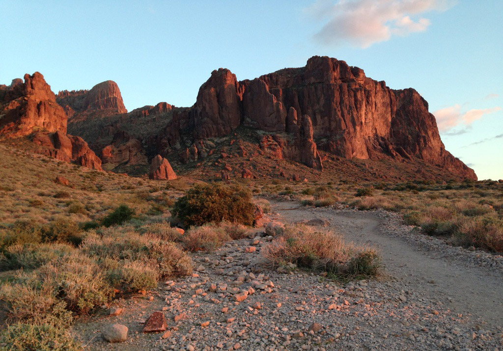 In the distance the low sun hits red rock cliff faces.