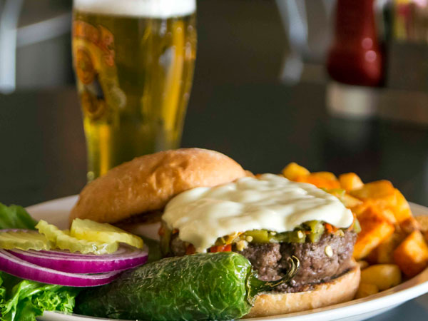 A cheeseburger on a plate with green chile sauce.