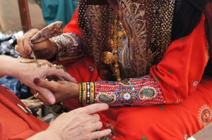 Close up of a woman in traditional garb applying henna to a visitor's skin.