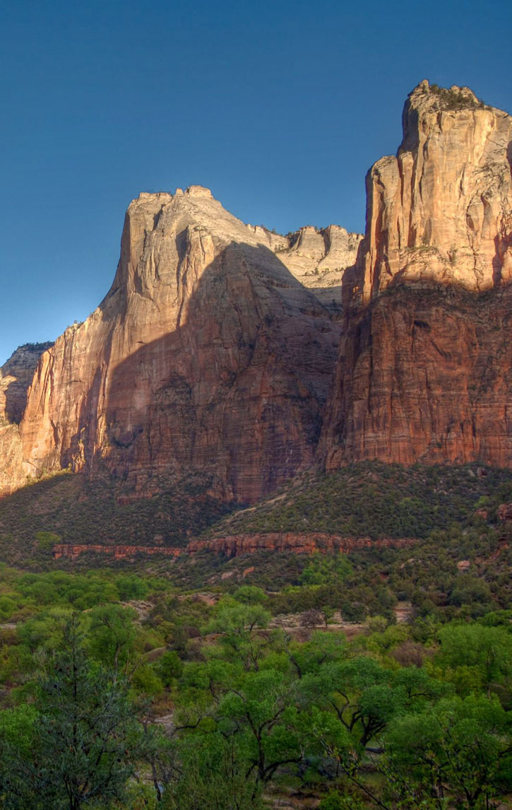 Shadows make a sharp line halfway up the steep peaks of the Court of the Patriarchs in Zion National Park.
