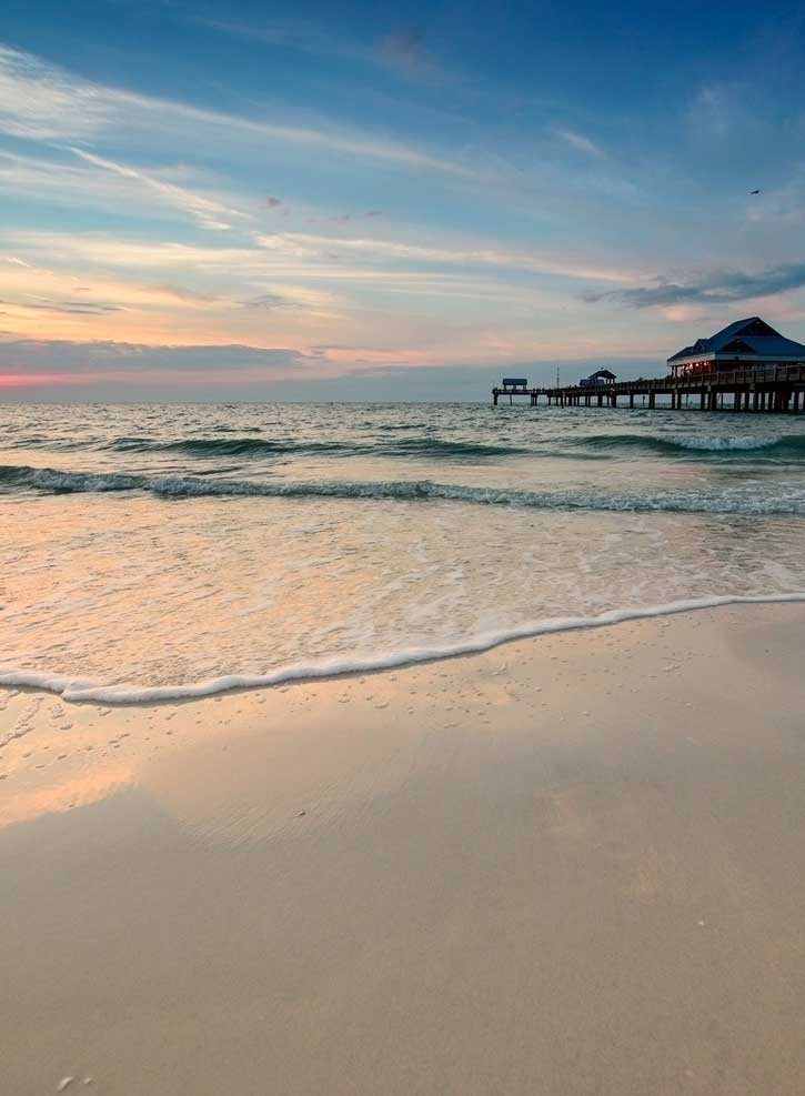 Low waves roll in past a long pier at Clearwater Beach, Florida.