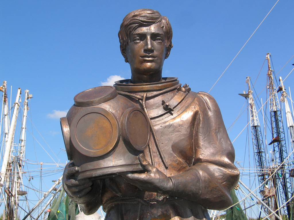 A bronze statue of a man holding a diver's helmet.