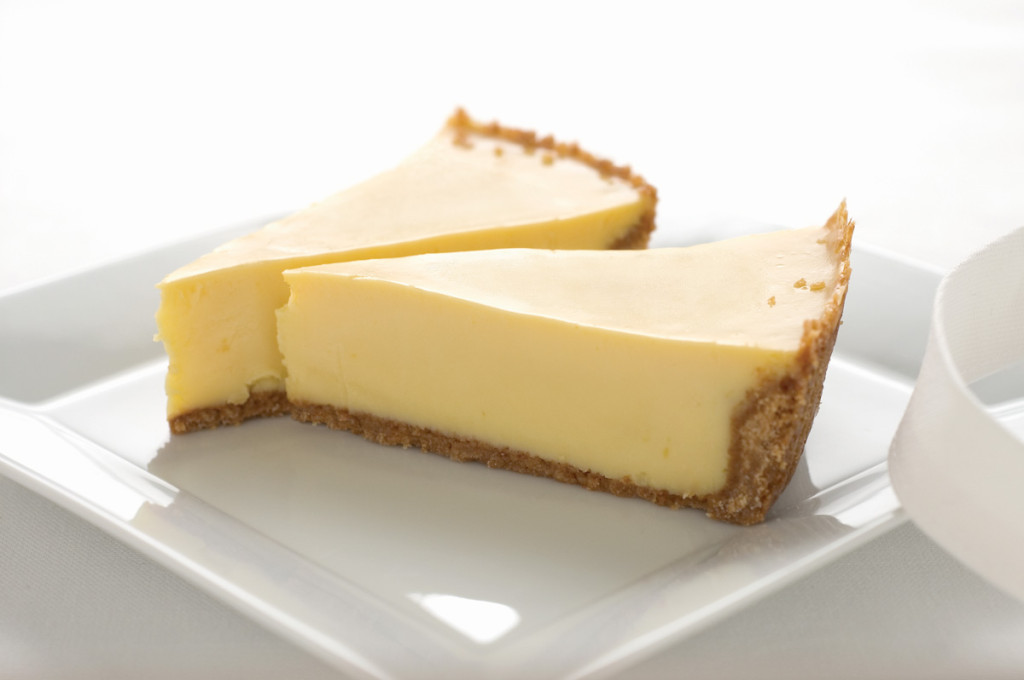 Two slices of key lime pie with a graham cracker crust plated on a square white plate.
