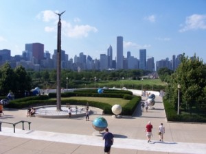 Pedestrians enjoy a plaza with Chicago's dramatic city skyline visible in the distance.