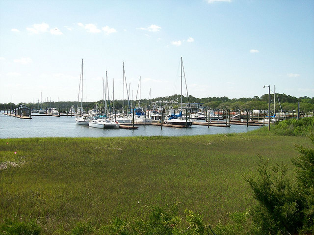 Grass grows up to the edge of the water where sailboats are docked in Southport.