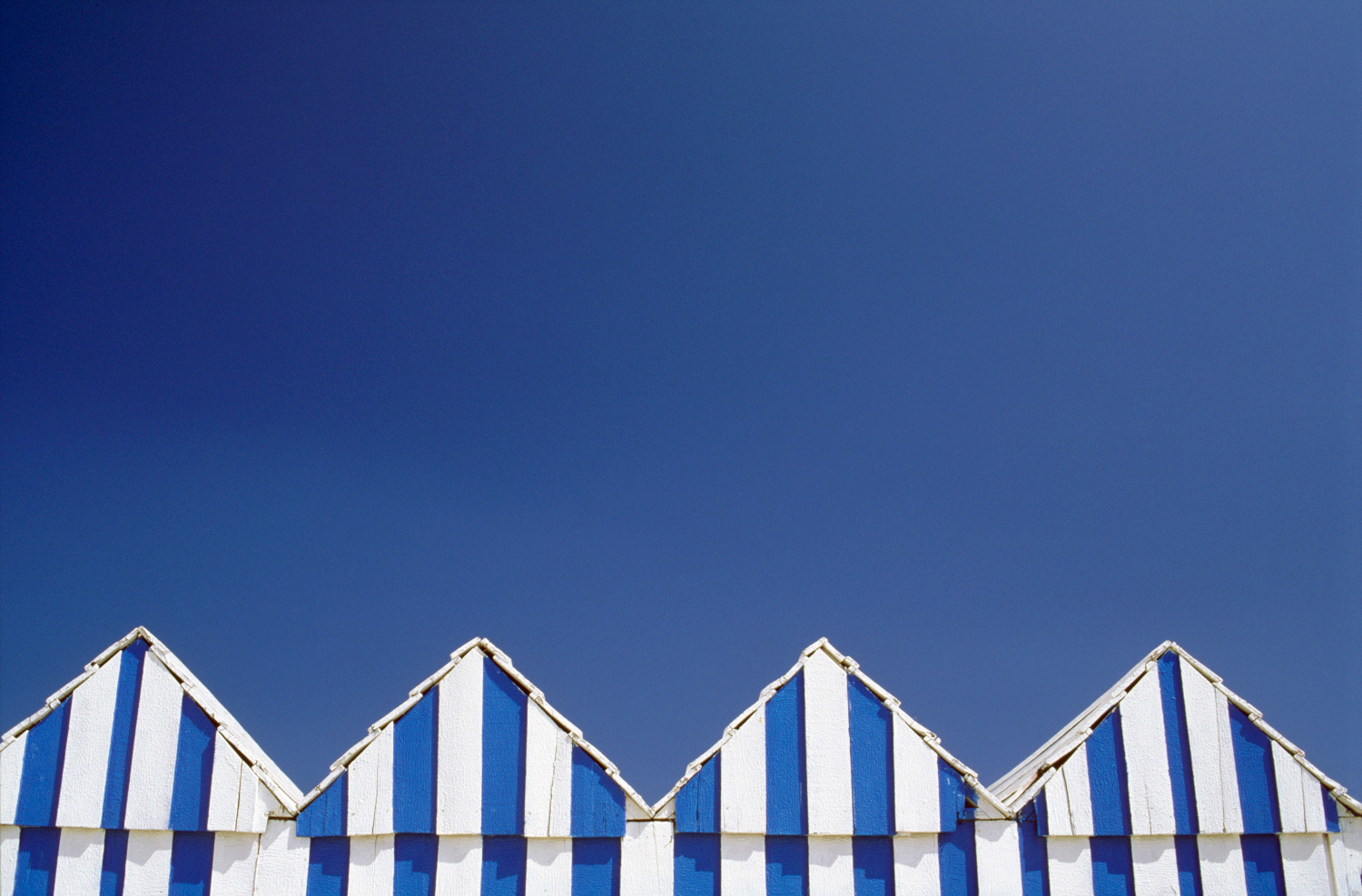 Beach huts huddle on Ilha de Tavira, where visitors can camp over. Image by Travel Ink / Gallo Images / Getty