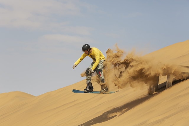 Pick up some speed sandboarding Dubai's dunes. Image by Thomas Dressler / Gallo Images / Getty