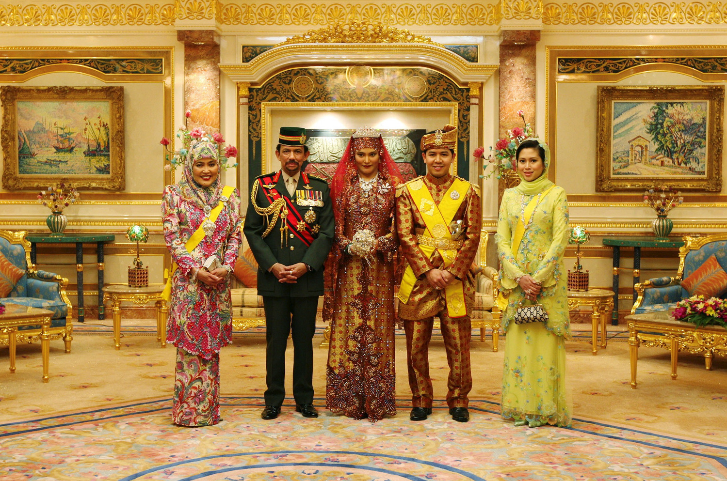 Sultan Hassanal Bolkiah is accompanied by Queen Consort Saleha (left) and third wife Azrinaz Mazhar (far right) at the wedding of his daughter Majeedah to Khairul Khalil (centre) © Pool Interagences / Getty Images