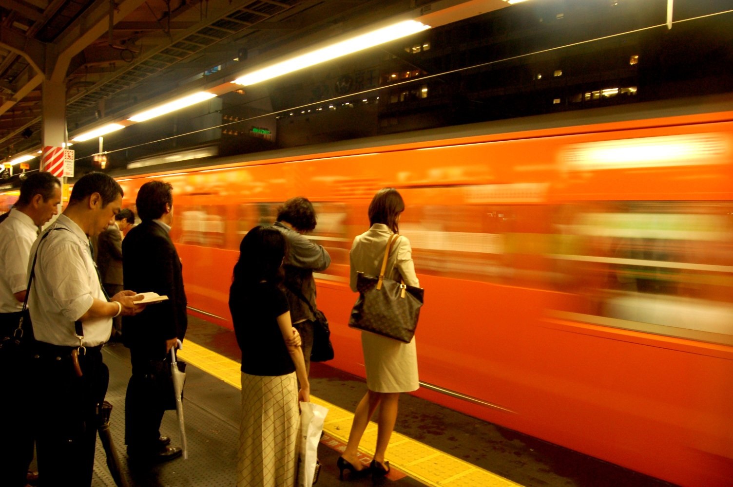 Passengers wait to board a train at Shinjuku Station