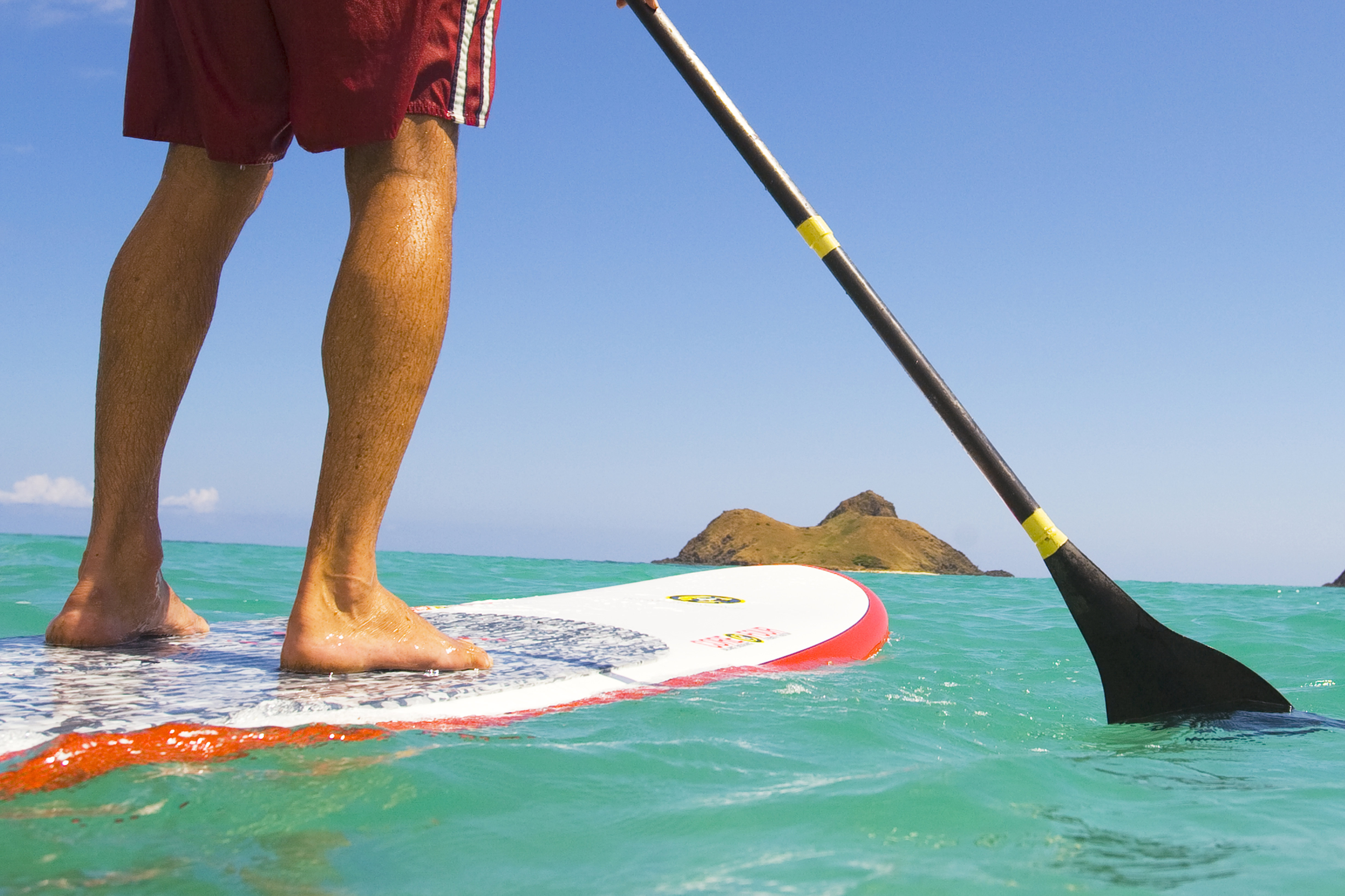 A stand-up paddleboarder off the coast of O'ahu. Image by Dana Edmunds / Getty