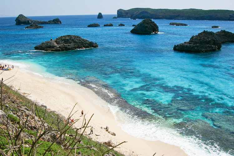 White sand tropical beach with clear blue water and coral rocks, Ogasawara Islands, Japan. Image by Ippei Naoi / Flickr Getty Images.