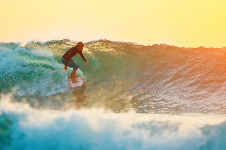 A surfer catches an evening wave off Bali. Image by Andrey Artykov / Vetta / Getty Images