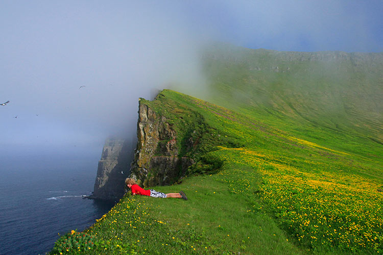 A hiker peers over sea cliffs Iceland. Image by Johnathan Ampersand Esper / Aurora / Getty Images