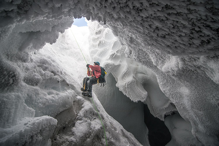 A scientist climbing out of a steam cave near Mount Erebus, Antarctica. Image by Alisdair Turner Photography / Flickr / Getty Images.