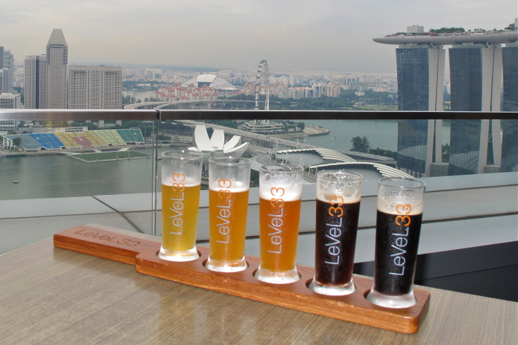 A row of beers with a backdrop of Singapore's skyline, seen from Level33 bar