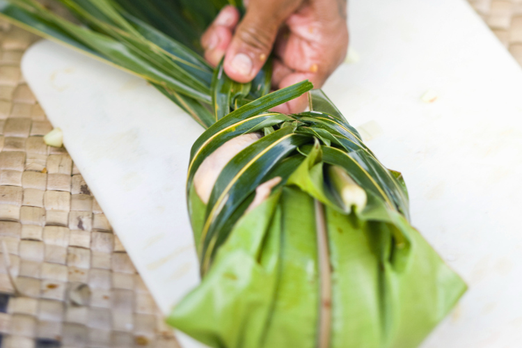 Preparing taro to be cooked in the fire pit. Image by Danita Delimont / Gallo Images