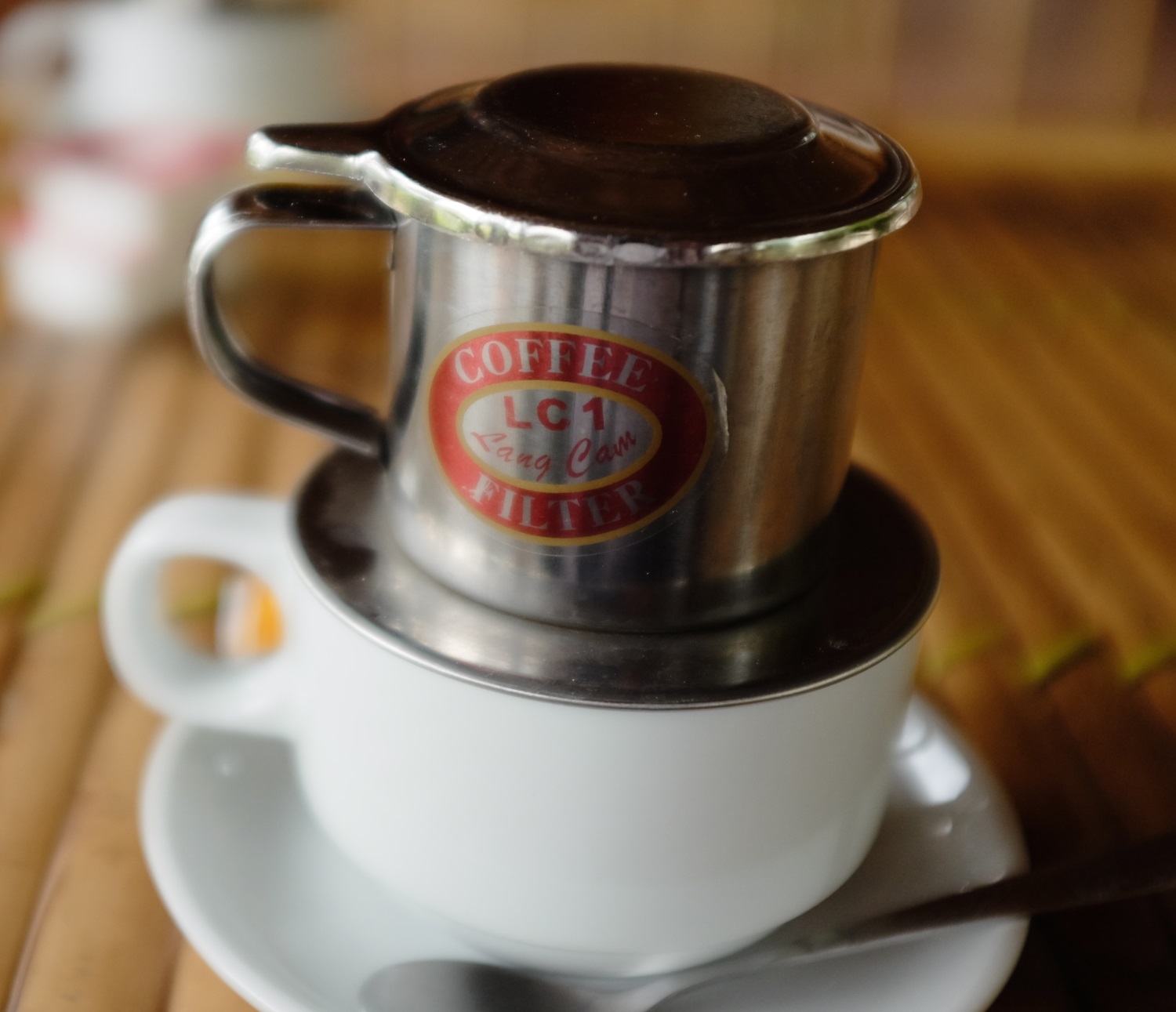 Coffee filters through a phin atop a coffee cup