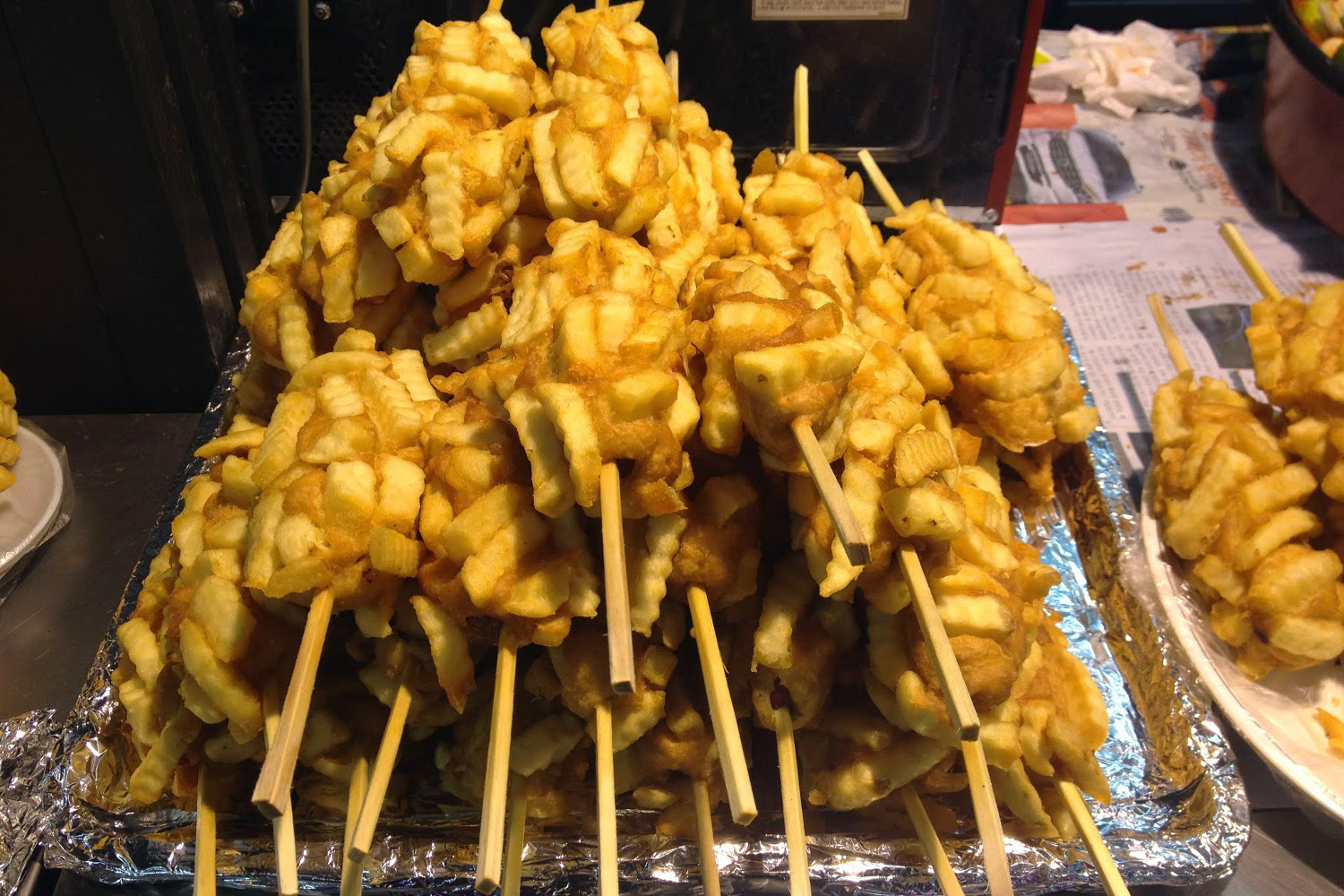 Epic corn dog covered in fries and served on a stick. Image by Megan Eaves / Lonely Planet