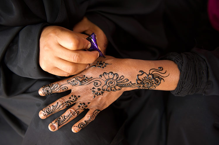 A Swahili woman painting hands with henna. Ariadne Van Zandbergen / Lonely Planet Images / Getty Images