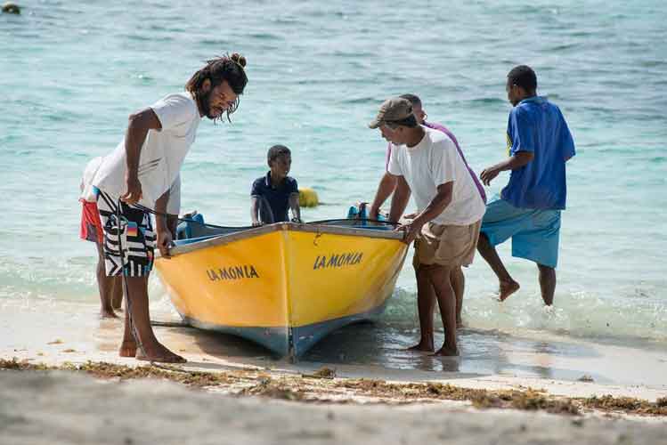 Locals haul in a boat on the quiet island of La Digue. Image by Oliver Berry / Lonely Planet.