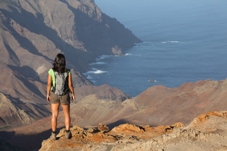 Hiker looking down to Sandy Bay, St Helena. Image by Darrin Henry / Lonely Planet