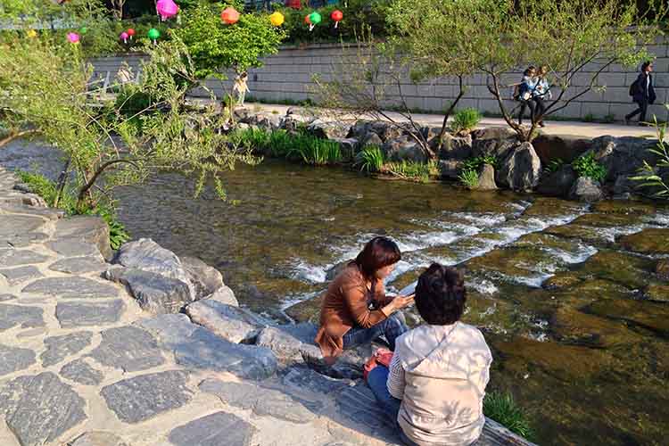 Locals relaxing by the Cheonggyeong Stream. Image by Tim Richards / Lonely Planet