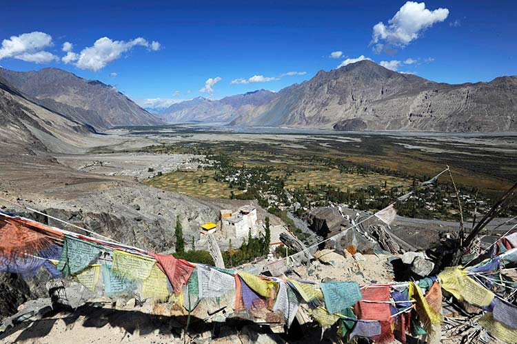 Overlooking the Shyok River's broad valley, prayer flags crest a small watchtower in the stark hillside above Diskit Monastery. Image by Amar Grover / Lonely Planet.
