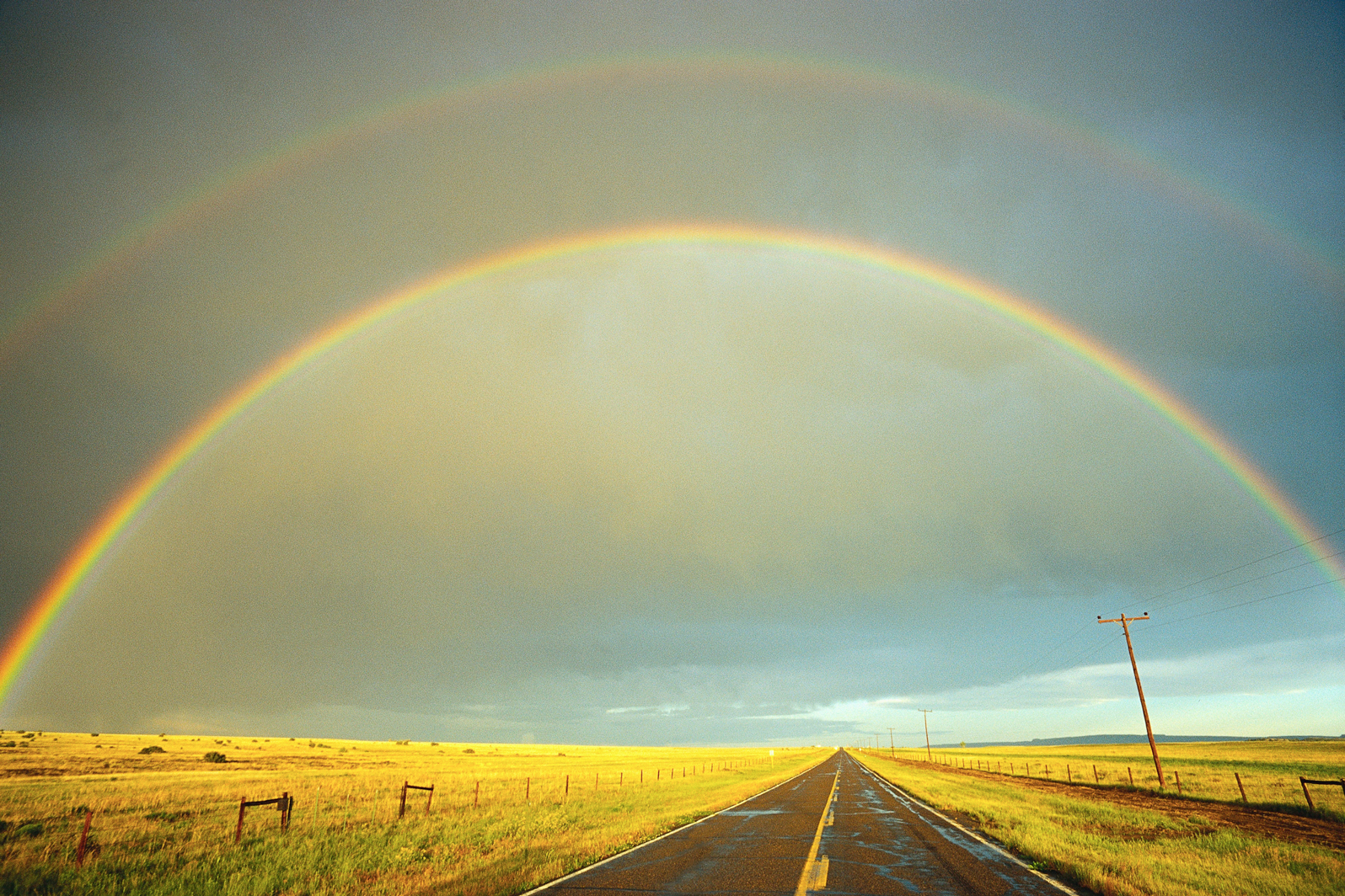 A rainbow stretches over a country road in Kansas. Image by Fuse / Getty