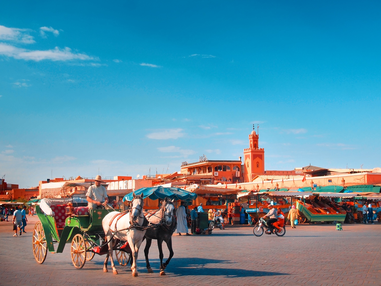 A horse and carriage drive through a sunny Djemaa el-Fna. Image by Alberto Manuel Urosa Toledano/Moment Editorial/Getty Images 