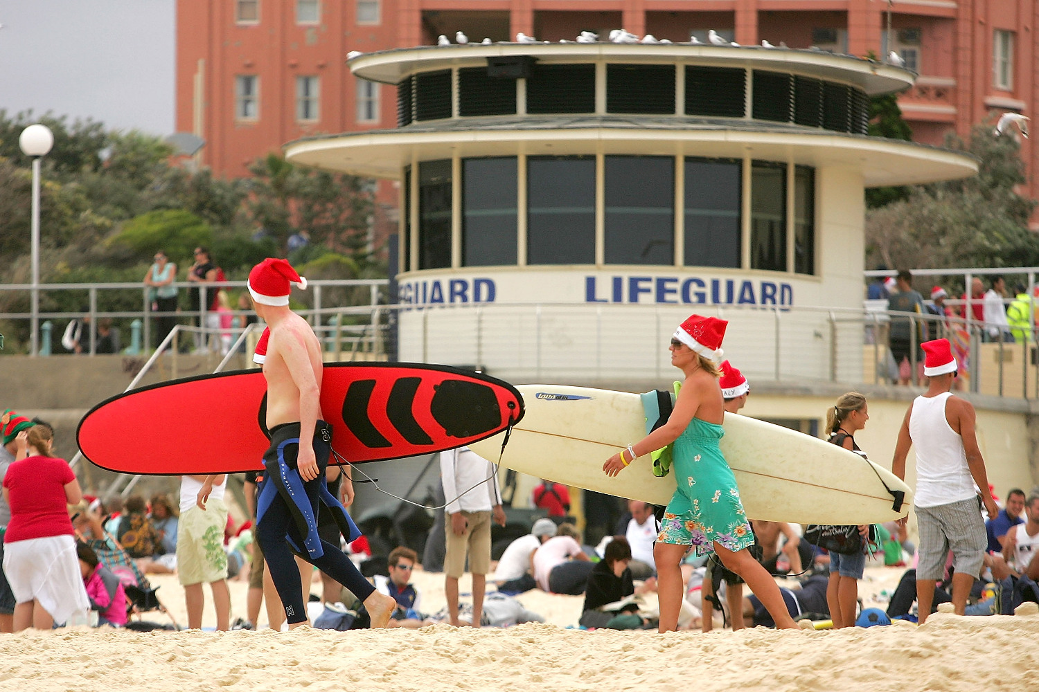 SYDNEY, AUSTRALIA - DECEMBER 25: Surfers wear Santa hats as walk down Bondi Beach on December 25, 2007 in Sydney, Australia. Bondi Beach is a popular destination for tourists on Christmas Day. (Photo by Ezra Shaw/Getty Images)