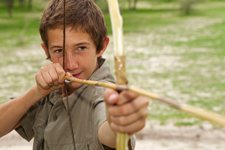 Learning the San art of hunting with a bow and arrow. Image courtesy of Ker & Downey Botswana