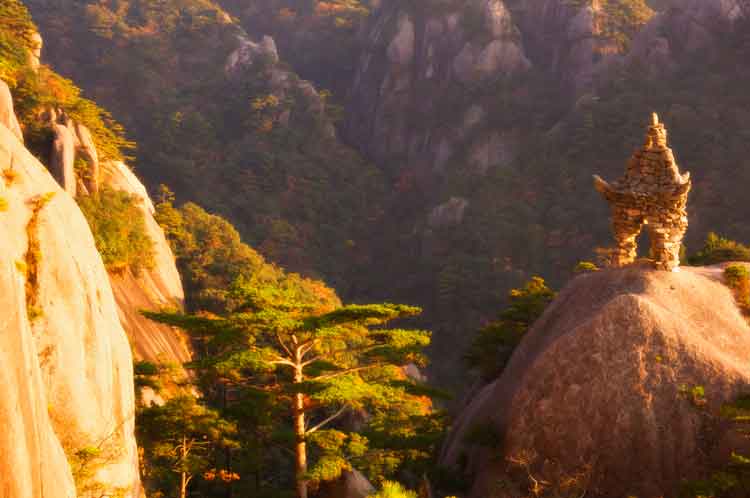 Stone sculpture crowning a peak in China's Yellow Mountain region. Image by Jochen Schlenker / Robert Harding World Imagery / Getty Images.