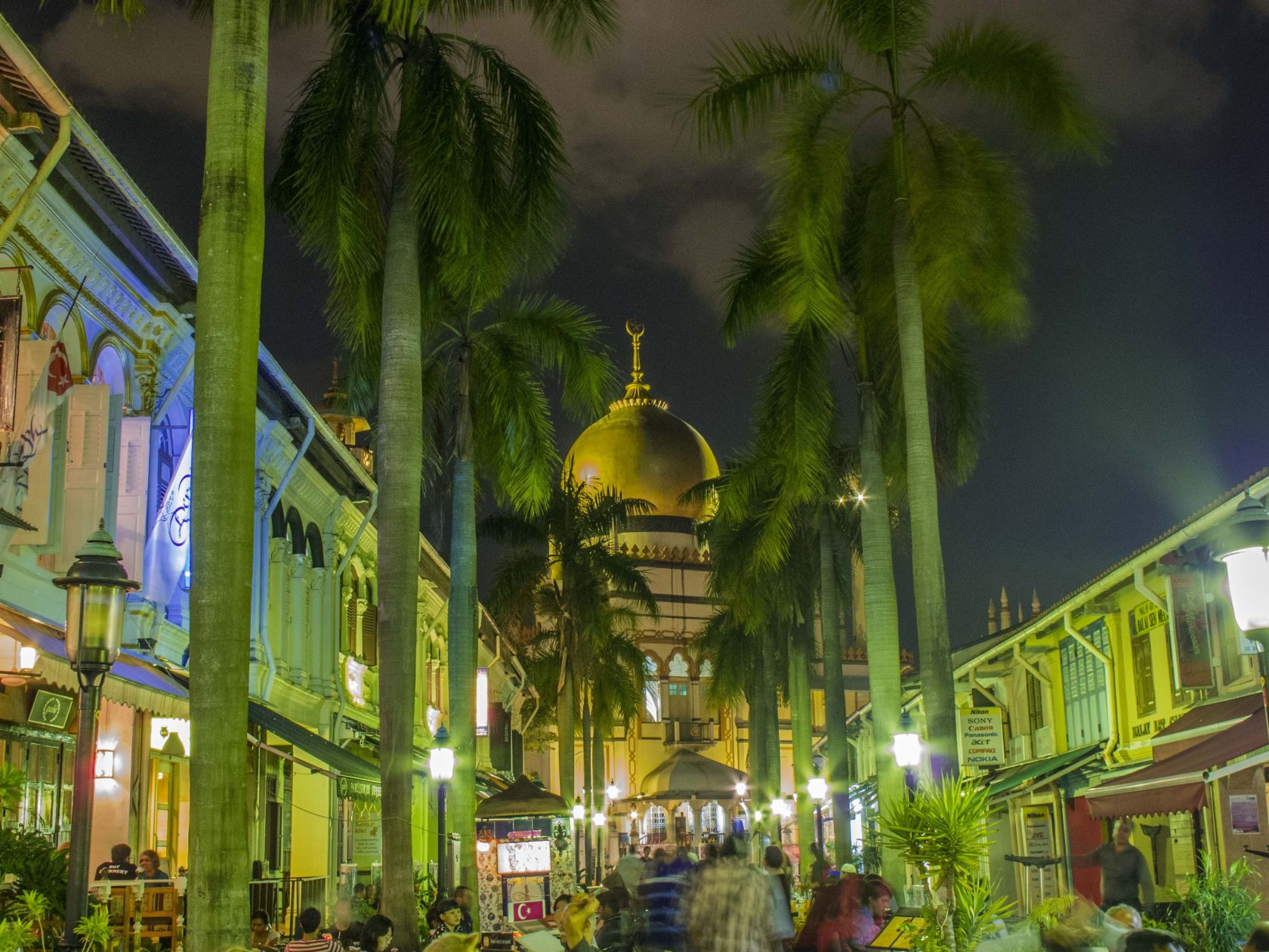 Sultan Mosque by night with busy terrace restaurants