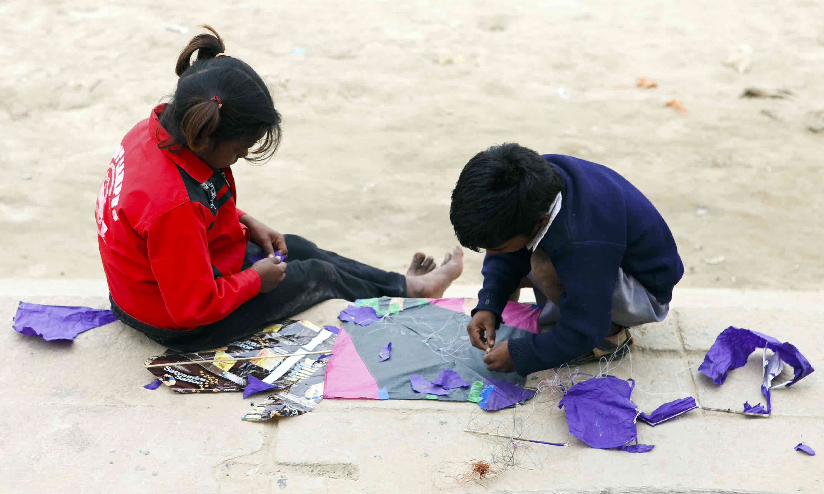 Children repair a kite on the banks of the Ganges (Shutterstock)
