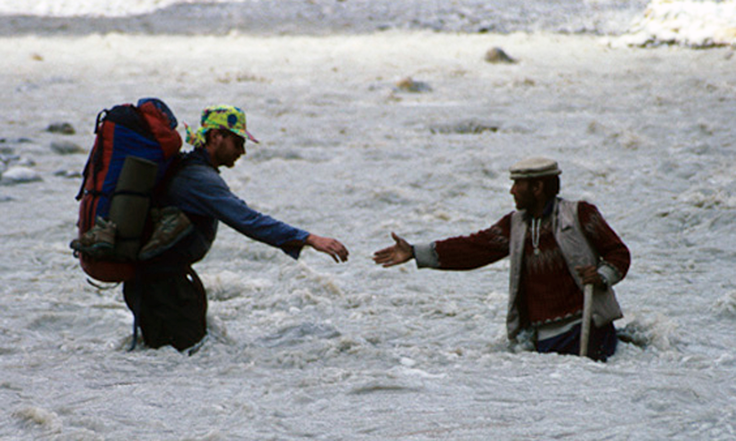 Andy Cave helped across river by a porter (Andy Perkins)