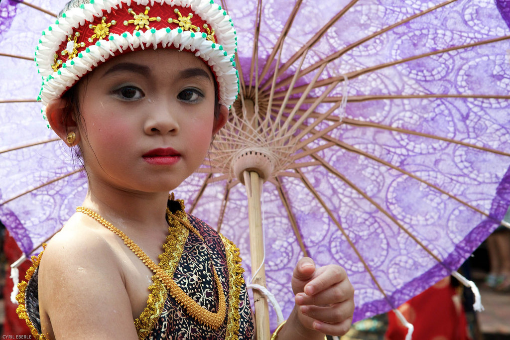 Little girl wearing traditional dress holding a purple umbrella at Lao New Year Parade