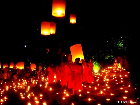 Novice monks surrounded by candles release sky lanterns during Loy Krathong Festival