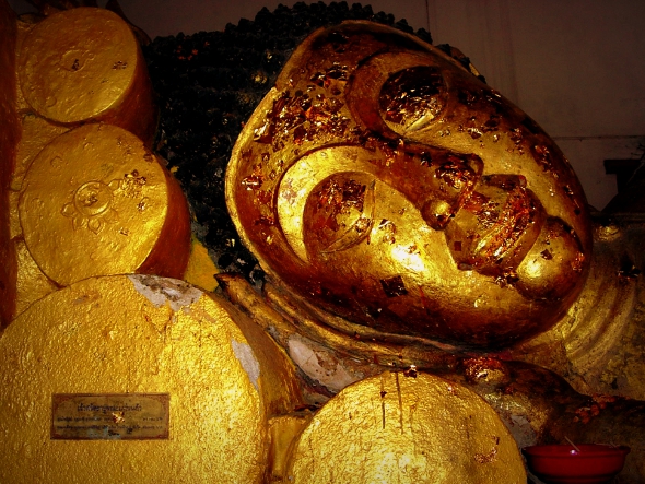 Small squares of gold leaf on reclining Buddha image