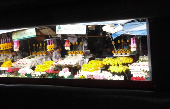 Roadside flower market viewed through the side window of a moving songthaew
