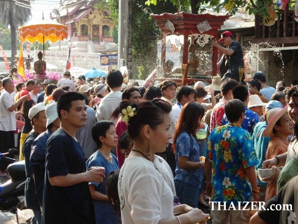 crowds gather to pour water over Buddha images as they are paraded through the streets during the Songkran Festival