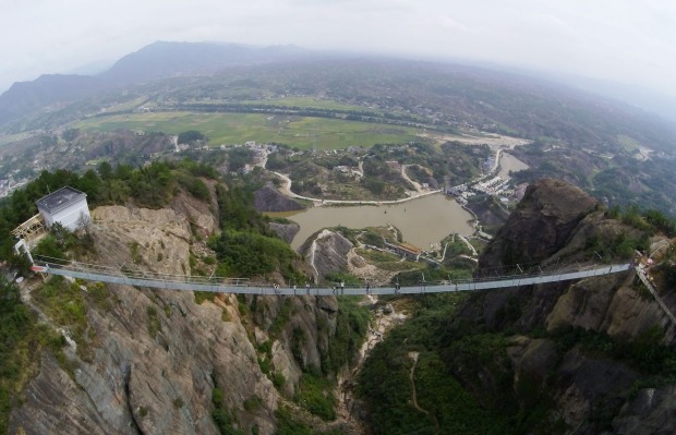Tourists walk on the 300-metre suspension bridge made of glass at the Shiniuzhai National Geological Park, China. ...