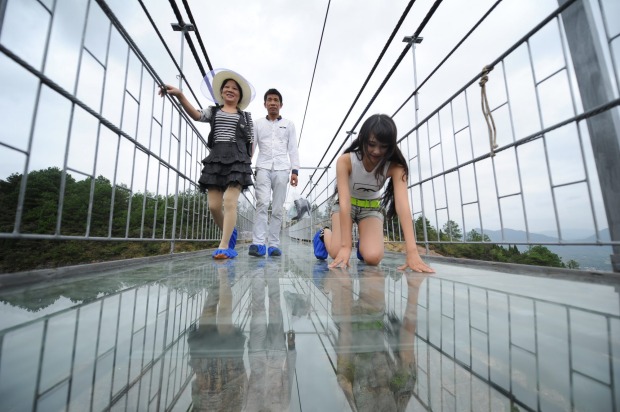 Tourists walk on the 300-metre suspension bridge made of glass at the Shiniuzhai National Geological Park, China. ...