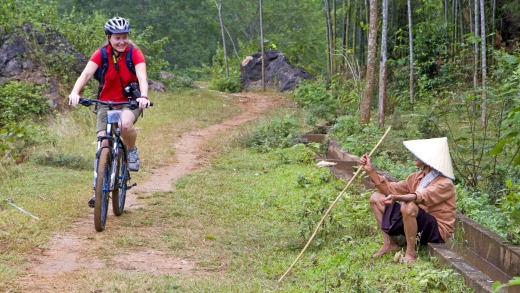 A cyclist passes  a buffalo herder near Mai Chau.